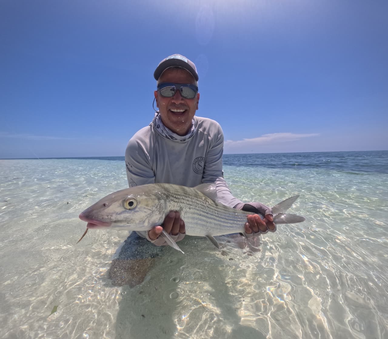 Angler holding a silver bonefish caught on fly in the shallow flats of Arrecife Alacranes.