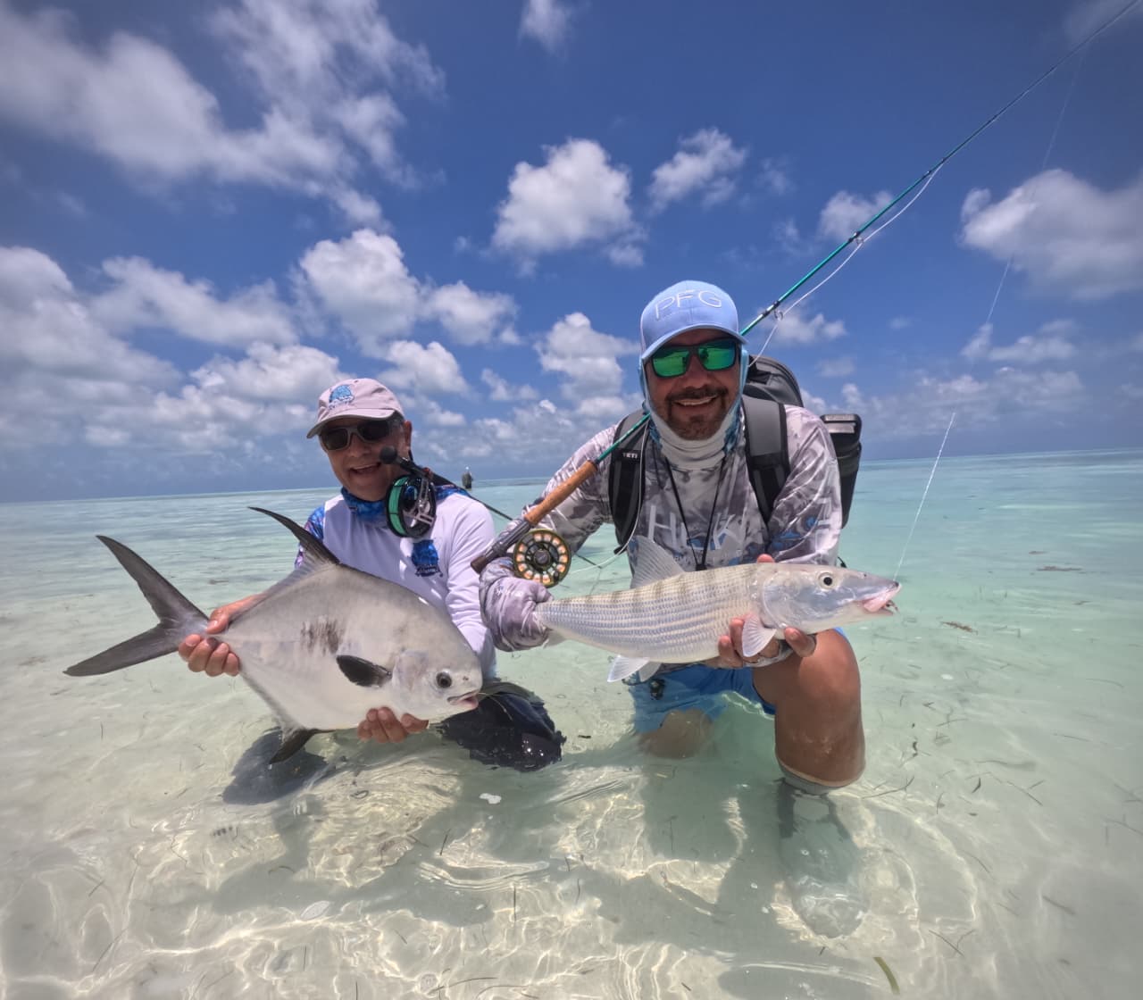 Anglers holding a silver bonefish and a permit caught on fly in the shallow flats of Arrecife Alacranes.